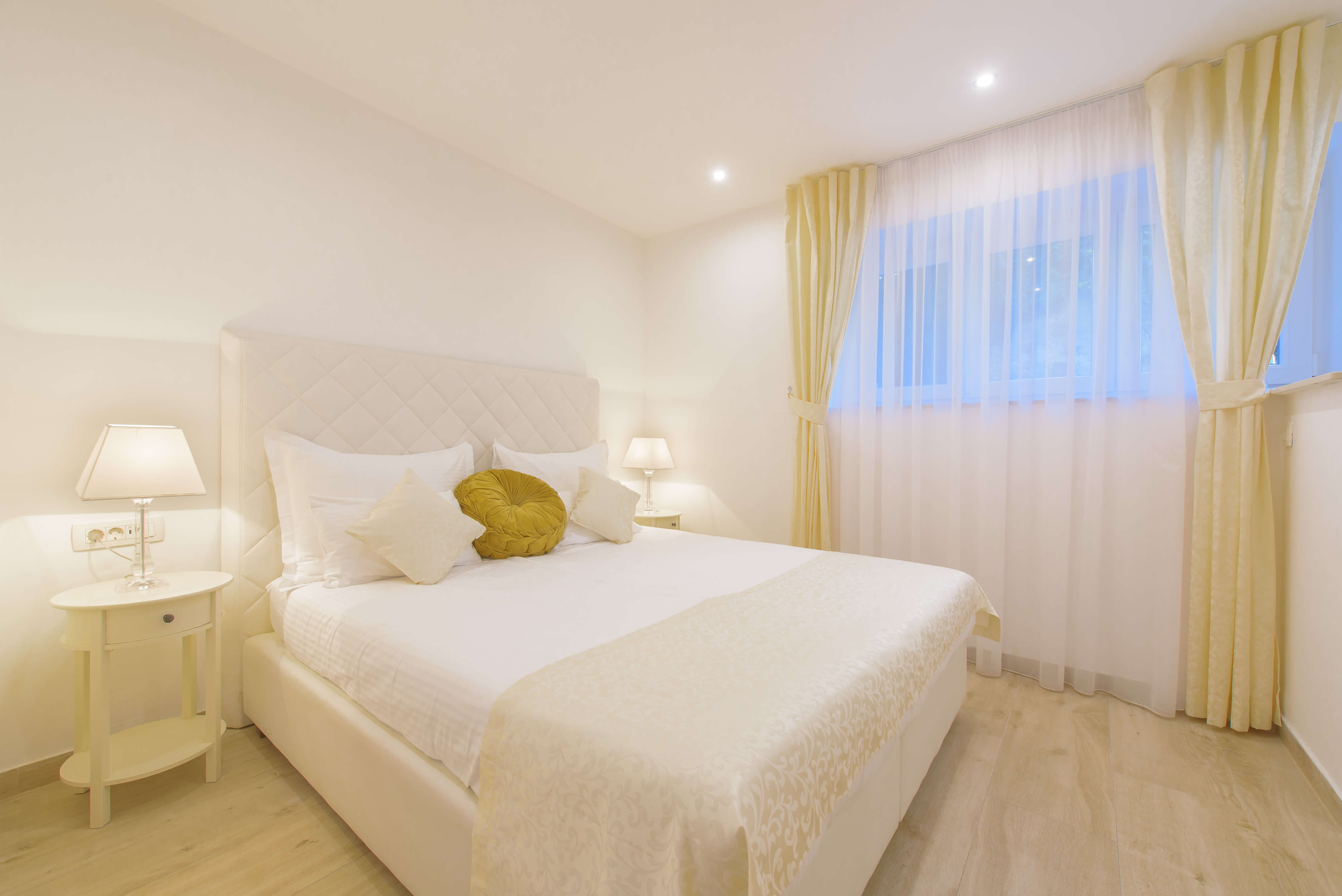 Schlafzimmer in den Best Location Apartments mit weißen Möbeln und einem goldenen Kissen